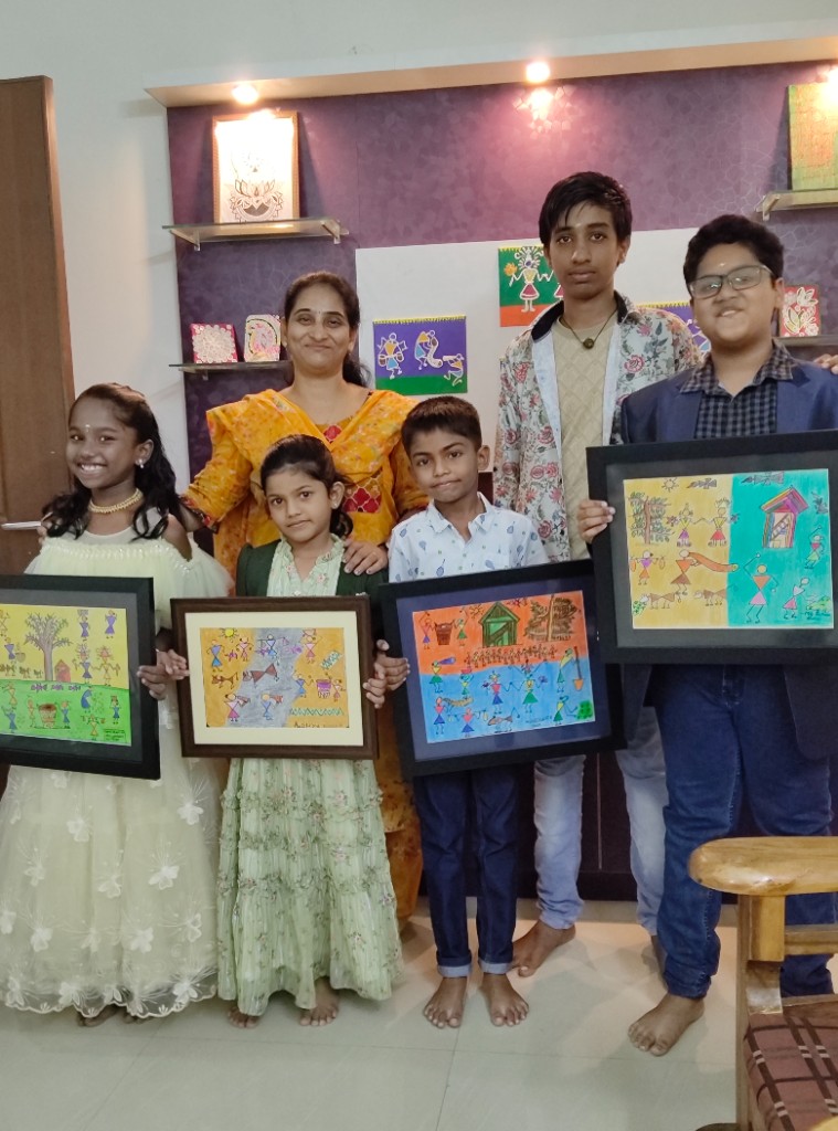 Children holding framed folk art pieces with their instructor