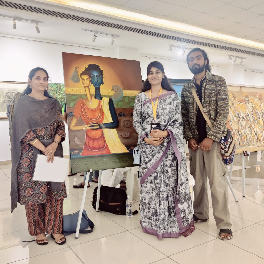 Artists and visitors at a gallery exhibition with a folk painting on display